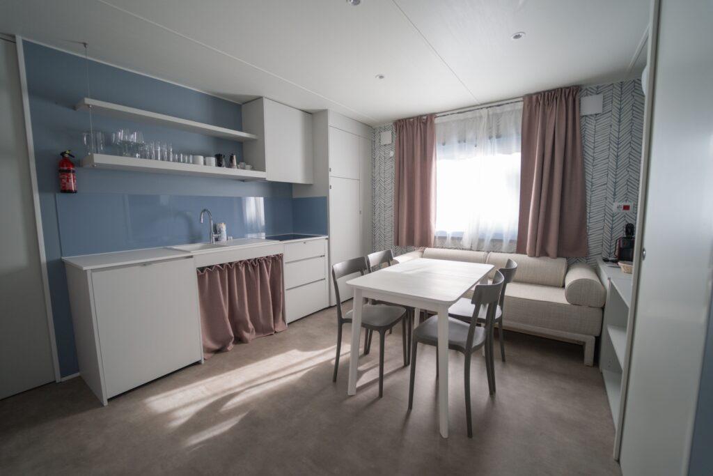 Zona giorno della Suite Mediterranea Open con cucina attrezzata, tavolo e divano.