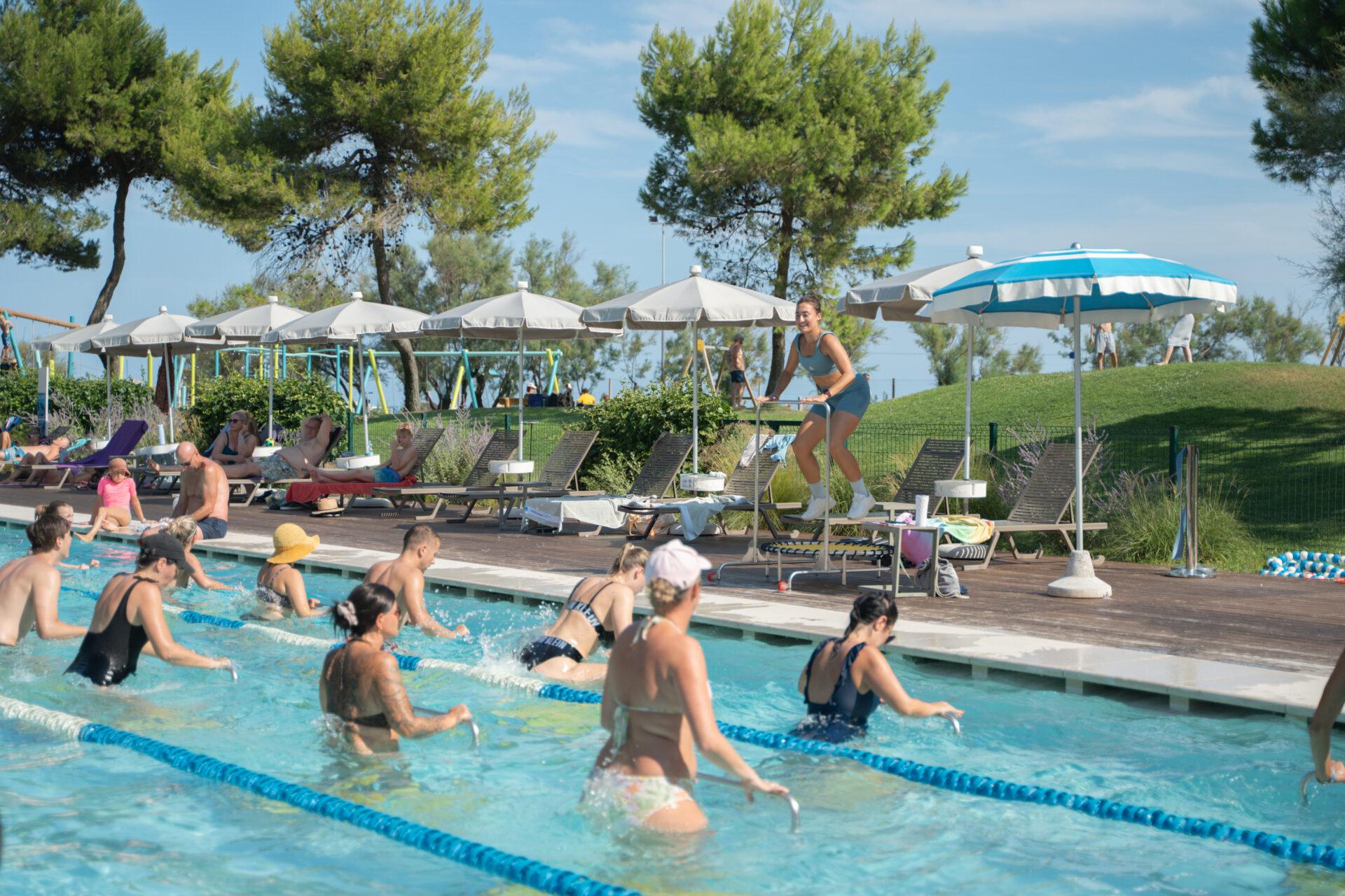 Ospiti si allenano sui trampolini elastici immersi in piscina durante una lezione di aquajump al Camping Mediterraneo