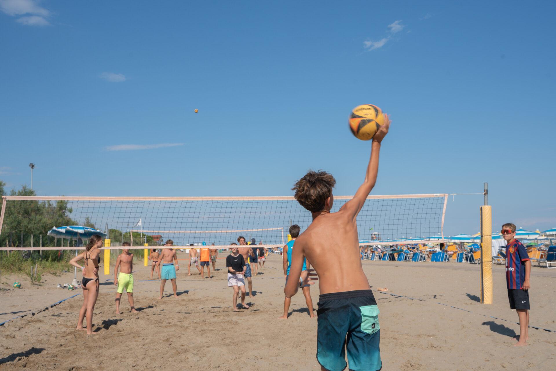 Ragazzo alza il pallone durante una partita di beach volley con altri giovani sulla spiaggia del Camping Mediterraneo