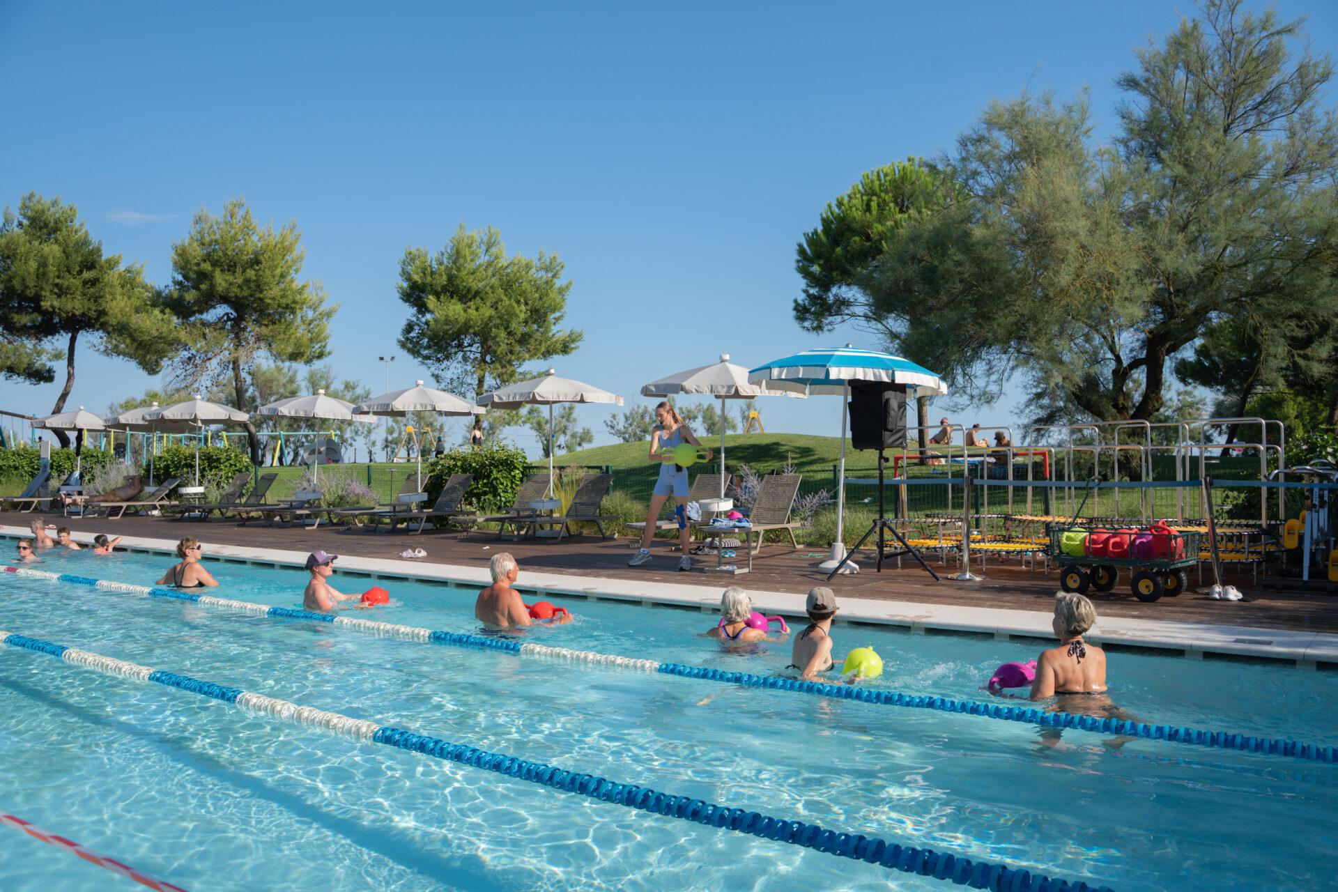 Ospiti utilizzano attrezzi acquatici colorati durante una lezione di Aqua Squid nella piscina del Camping Mediterraneo