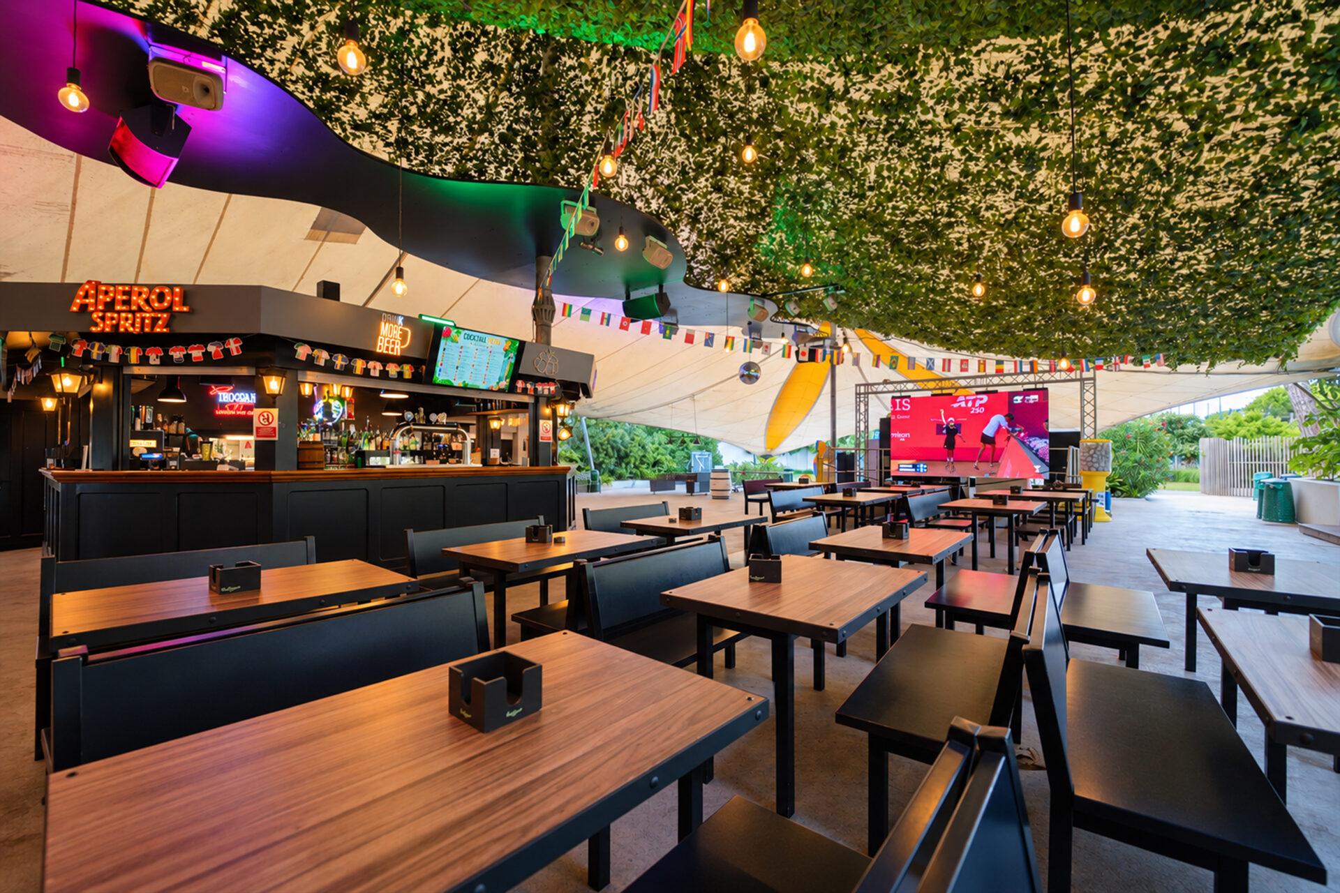 Bar e tavoli con maxischermo a La Serra Sport & Lounge del Camping Village Mediterraneo