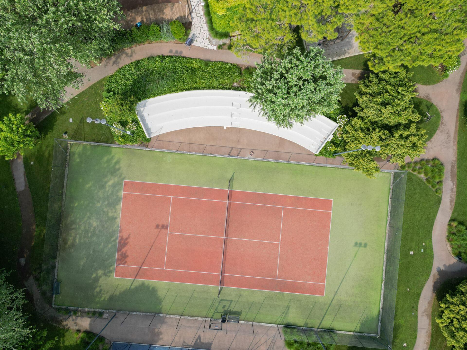 Vista aerea del campo da tennis de La Serra Sport con superficie rossa e verde, circondato da alberi e vialetti